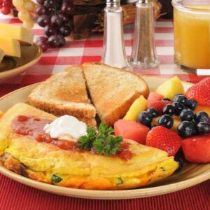 breakfast of an omelette, fruit, and toast with orange juice