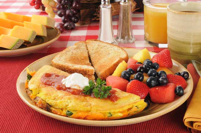 breakfast of an omelette, fruit, and toast with orange juice