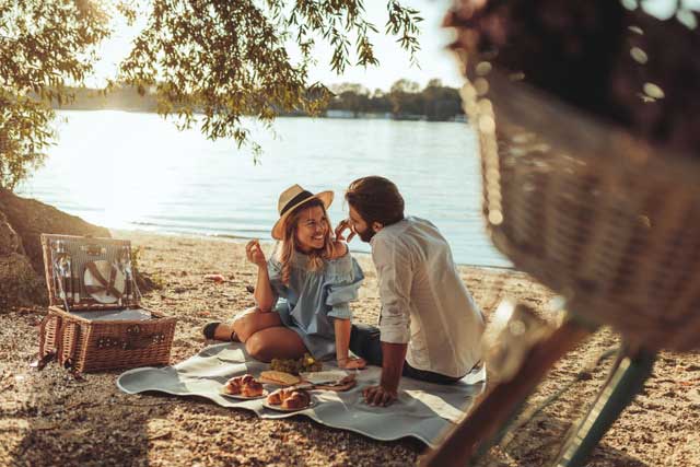 woman and man having a picnic by a river with a picnic basket