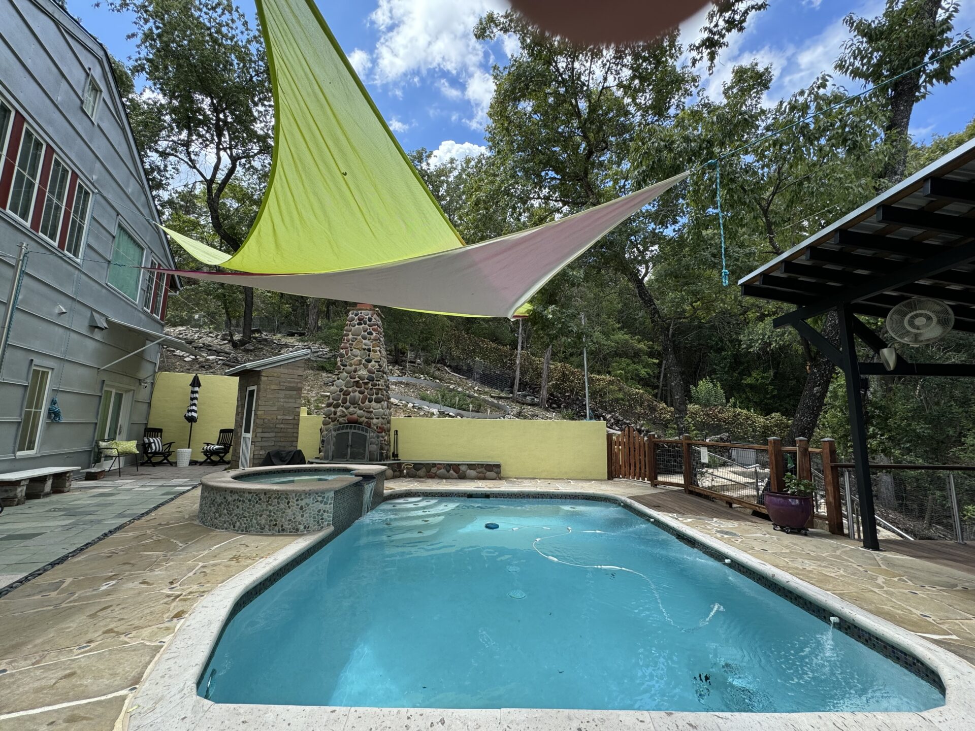 Swimming pool area with shade sails and hot tub