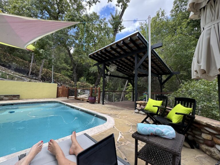 Covered pergola at pool area with people seated and feet showing